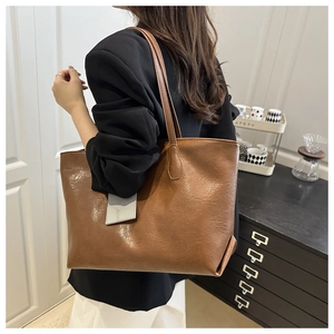 Detail of caramel brown tote bag with pleated leather texture and geometric charm