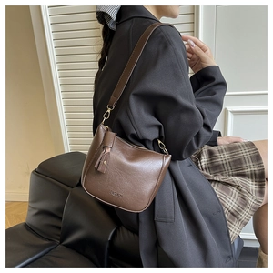 Brown leather crossbody bag with FASHION embossed logo and gold metal hooks worn by a model