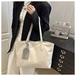 Detail of off-white tote bag with lychee texture and decorative grey leather tag