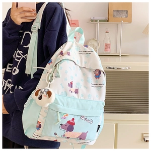 Detail of mint green school backpack featuring cute dog prints and plush pendant