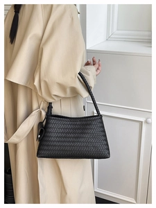 Close-up of black woven leather handbag showing classic intrecciato texture and style