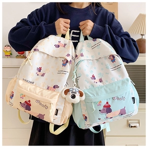 Detail of cute cartoon backpacks in beige and light blue with plush dog charm accessories