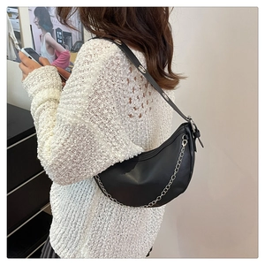 Detailed view of a black Hobo bag with silver chain worn by a model in a knit sweater