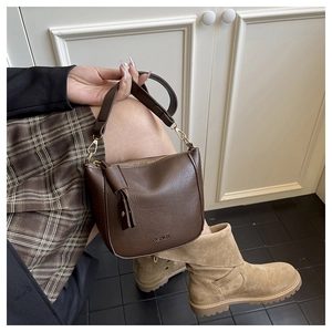 Close-up of deep brown lychee texture leather shoulder bag with wide strap detail