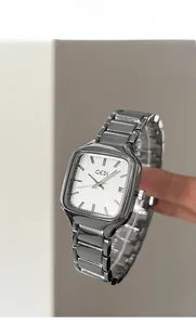 Détail d'une montre à quartz carrée argentée avec bracelet métallique et guichet de date blanc