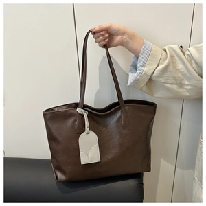 Close-up of brown faux leather tote bag texture with minimalist decorative hanging tag