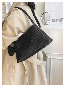 Detailed view of the woven leather texture and shoulder strap of the black tote bag