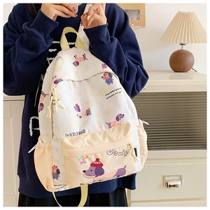Detail of cream backpack with cartoon puppy patterns shown in a cozy home setting