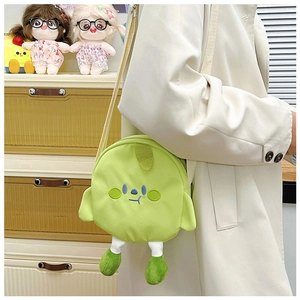 Close-up of a cute green plush crossbody bag with embroidered cartoon face and small legs