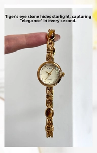 Detail of gold watch band featuring tiger eye stones and polished metal links