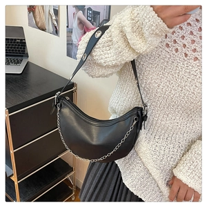 Detail of black leather half-moon bag with silver chain and metal eyelet shoulder strap