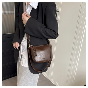 Détail du sac seau marron vintage avec logo FASHION et large bandoulière en cuir