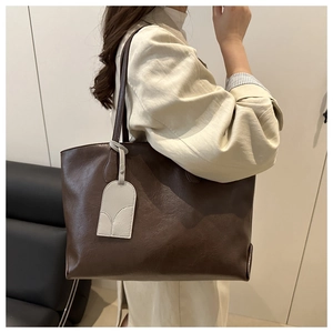Detail view of large dark brown soft leather tote bag with a beige decorative tag