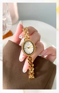 Close-up of vintage gold quartz watch with oval dial and decorative hollow metal bracelet
