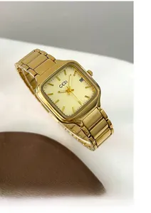 Détail d'une montre carrée dorée avec guichet de date et cadran champagne