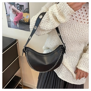 Detail of black crescent shoulder bag with silver chain and metal eyelet strap