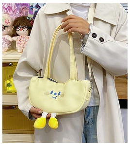 Close-up of pale yellow canvas bag featuring blue cartoon embroidery and plush 3D yellow feet