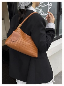 Detail of caramel brown woven leather shoulder bag with decorative knotted strap accents