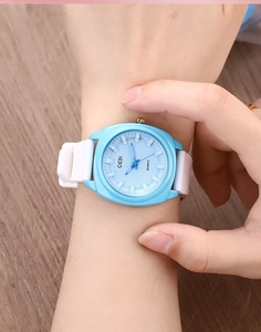 Close-up of light blue quartz watch with white silicone strap on wood background