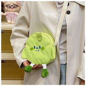 Close-up of cute green cartoon canvas crossbody bag with embroidery and plush legs