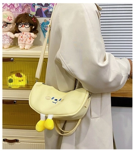 Close-up of cute yellow canvas crescent bag with cartoon embroidery and plush 3D doll legs