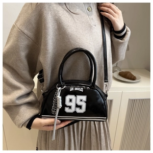 Close-up of black glossy leather bag with white Los Angeles 95 logo and silver chain