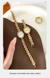Detail of GEDI small oval quartz watches with gold bamboo-style bracelet link on soft fabric
