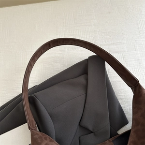 Brown suede leather underarm bag with wide strap paired with a grey wool blazer for commute
