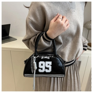 Detail of black patent leather tote with white Los Angeles print and silver chain