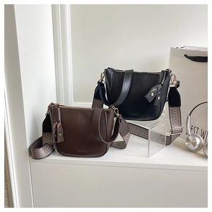 Detail of vintage bucket bags with wide geometric straps and FASHION embossed texture