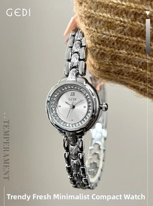 Close-up of elegant silver quartz watch with rhinestone bezel on knit sweater sleeve