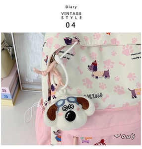 Close-up of cute cartoon pattern and plush dog keychain on pink school backpack