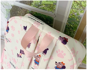 Close-up of the cute cartoon dog pattern and pink strap on the cream school backpack
