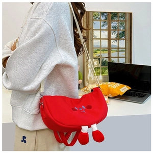Detail of red cartoon canvas crossbody bag with cute dangling legs and smiling face