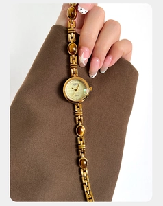 Close-up of golden quartz watch with tiger eye stone bracelet on a female model wrist