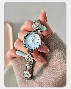 Détail d'une montre à chaîne argentée avec cadran en nacre bleue et ornements de perles