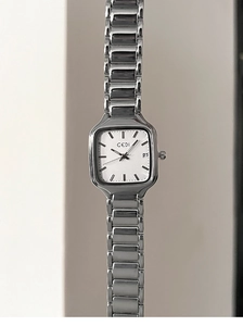 Détail macro du cadran rectangulaire argenté avec guichet de date et bracelet métal