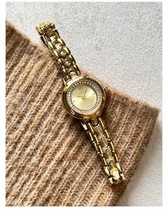 Detail of luxury gold women watch with rhinestone bezel and unique wavy textured chain band