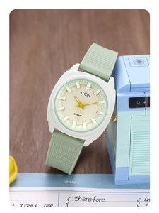 Detail showing white square matte watch case with green silicone strap and geometric dial