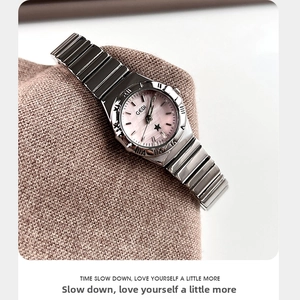 Detalle del reloj de mujer con esfera de nácar rosa sobre una tela de textura suave