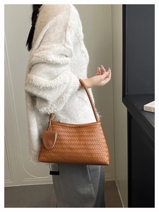 Detail of caramel brown woven hobo bag with matching strap on a model shoulder