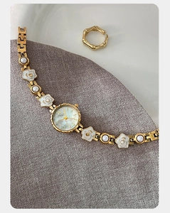 Gros plan d'une montre à quartz dorée avec bracelet floral et bague assortie