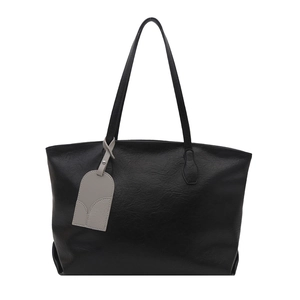 Large black leather tote bag with gray charm tag in a minimalist front view