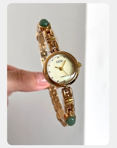 Macro detail of GEDI quartz watch featuring green stone inlays on a gold chain band