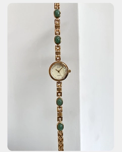 Macro detail of GEDI quartz watch featuring green amber stones and gold chain strap
