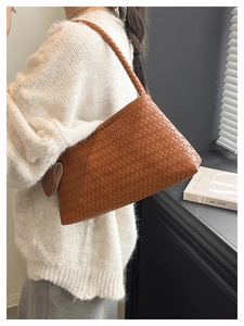 Close-up of brown woven leather hobo bag worn by model in a white knit sweater