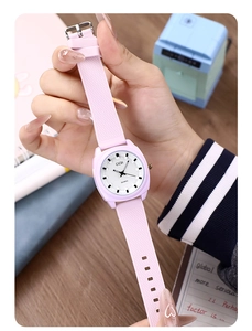 Detailed macro view of the pink silicone strap and square white dial of the quartz watch