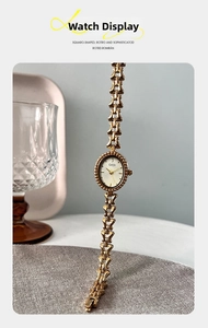 Close-up of vintage oval gold quartz watch with hollow chain bracelet on a tray