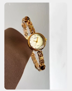 Macro detail of luxury gold chain watch featuring amber stone inserts and quartz dial