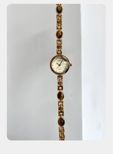 Detailed macro of gold GEDI quartz watch featuring amber stone inlays and elegant chain band